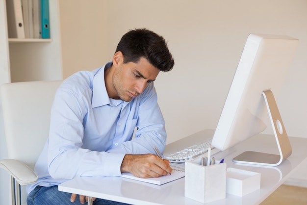 Casual businessman writing at his desk