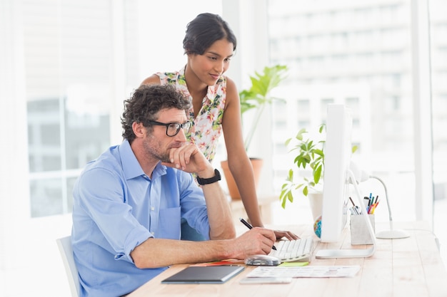 Casual businesswoman looking at colleagues computer