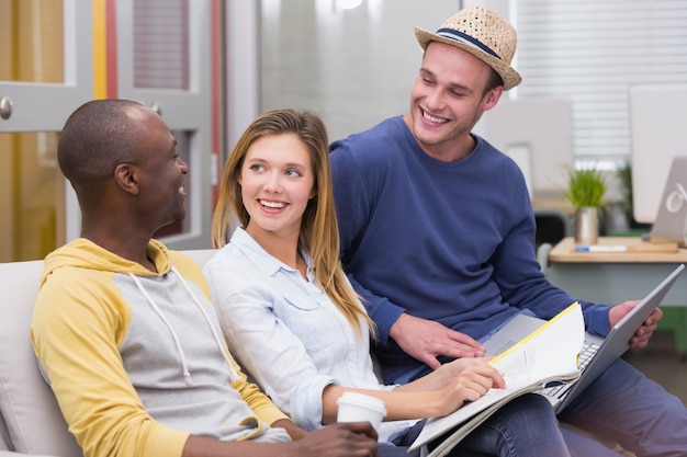 Casual colleagues using laptop on couch in office