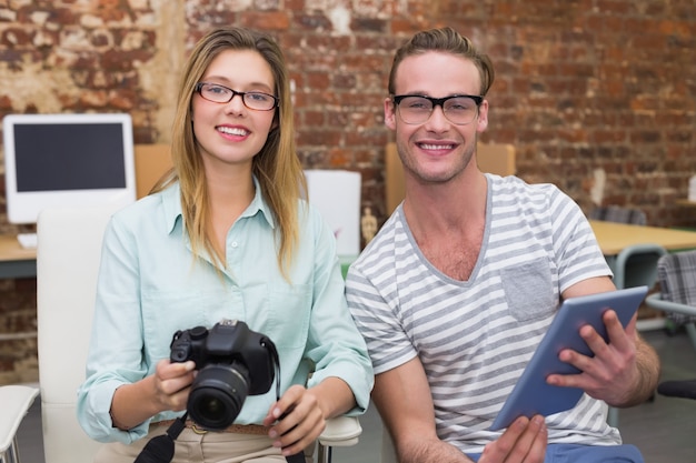 Casual colleagues with digital camera and tablet in office