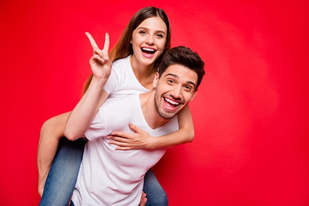 Casual couple posing against the red wall