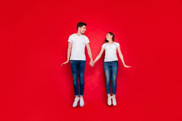 Casual couple posing against the red wall