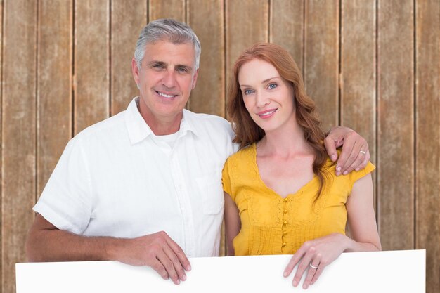 Photo casual couple showing a poster against wooden planks