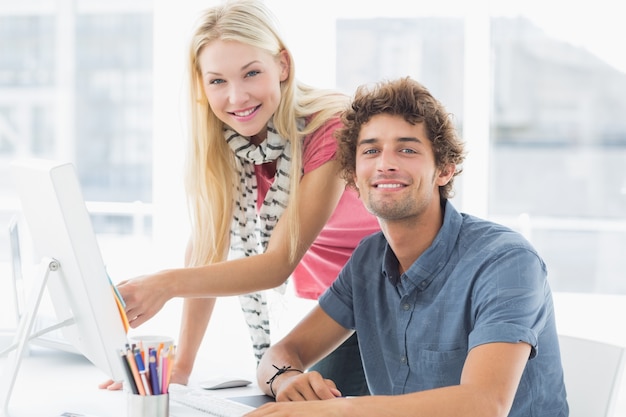 Casual couple using computer in bright office