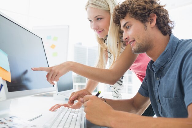 Casual couple using computer in office