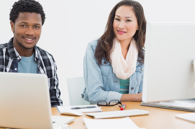 Casual couple using computers in office