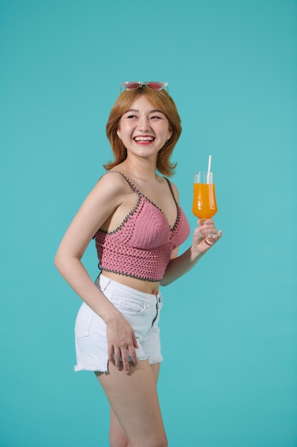 Casual dressed woman holding orange juice with glass isolated portrait smiling girl on turquoise background