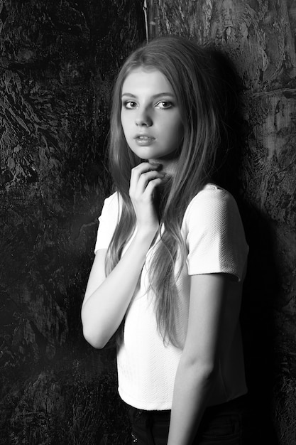 Casual dressed wonderful woman posing in a dark room. Black and white shot