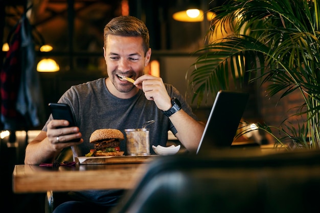 A casual entrepreneur is sitting on a lunch break and using cellphone at restaurant