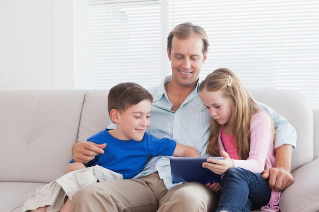 カジュアルな父親と子供たちがソファにタブレットを使用