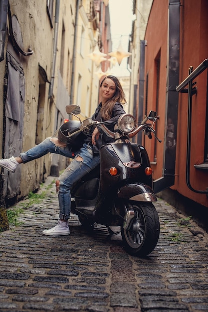 Casual female on moto scooter on the street in old town.