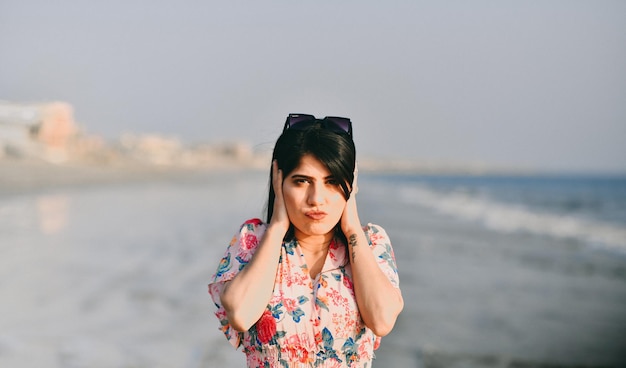 casual gelukkig mooi meisje beide handen op de oren vooraan poseren op het strand indisch pakistaans model
