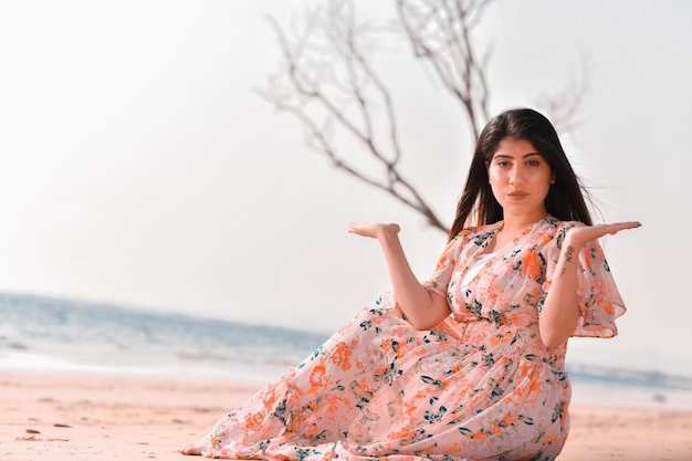 casual joyful pretty girl front pose sitting on beach indian pakistani model