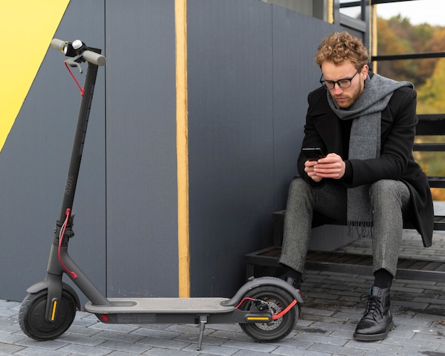 Foto maschio casuale in posa con il suo scooter elettrico