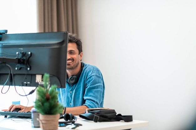 Casual man aan het werk op desktopcomputer in moderne open startup kantoor interieur selectieve focus