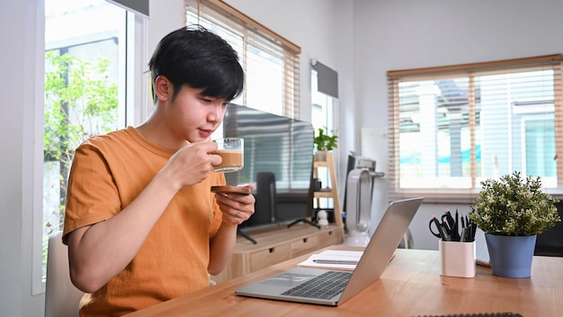 집에서 커피를 마시고 노트북 컴퓨터를 사용하는 캐주얼 남자.