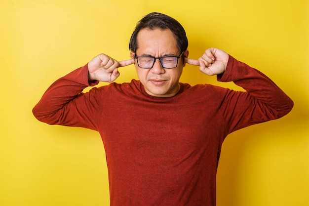 Casual man in glasses covering ears with fingers isolated on yellow background Annoyed Expression