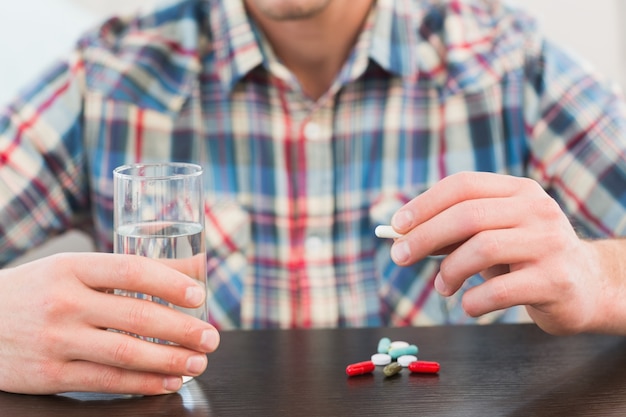 Casual man holding glass of water and tablet 