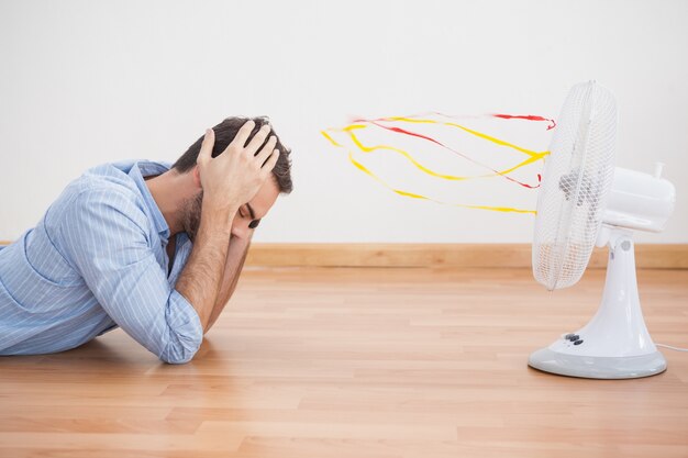 Casual man lying in front of fan