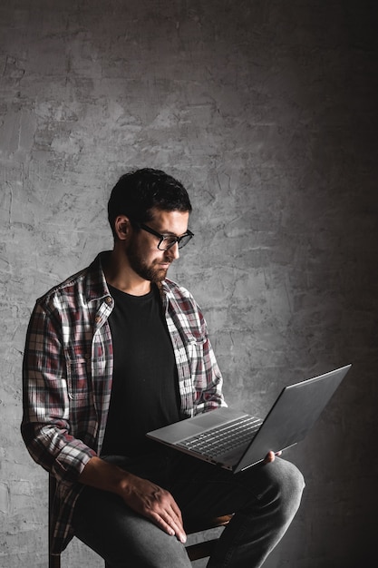 Casual man met laptop over grijze achtergrond. internet, onderwijs, werk, vrije tijd