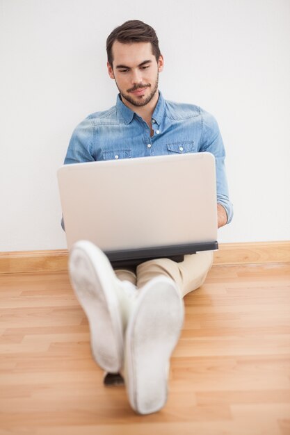 Casual man sitting on floor using laptop