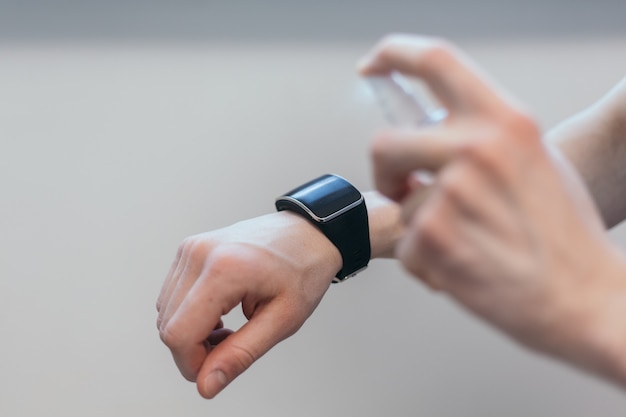 casual man spraying alcohol antiseptic on his smartwatch