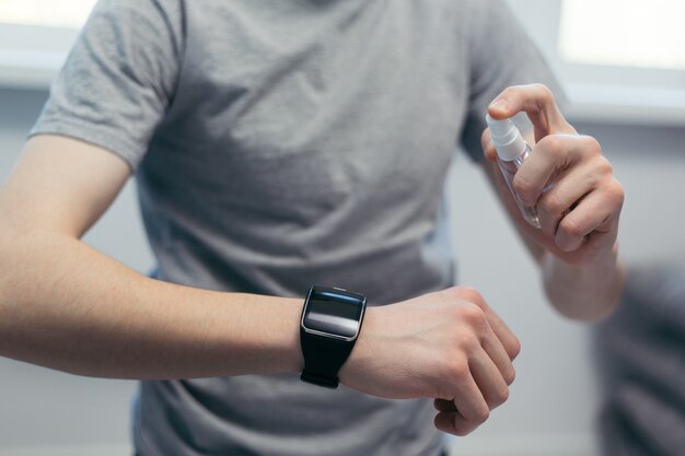 casual man spraying disinfectant on his smartwatch