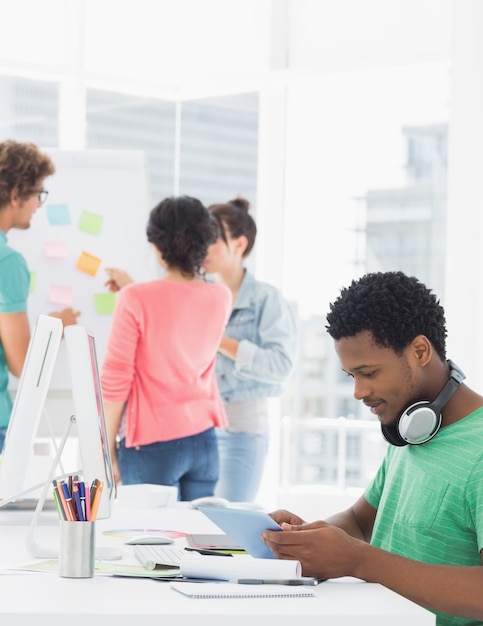 Casual man using digital tablet with colleagues behind in office