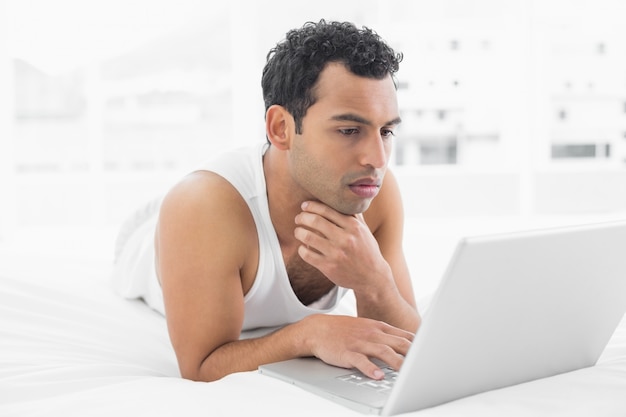 Casual man using laptop in bed