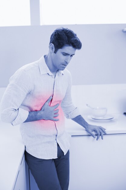 Casual man with stomach pain in the kitchen