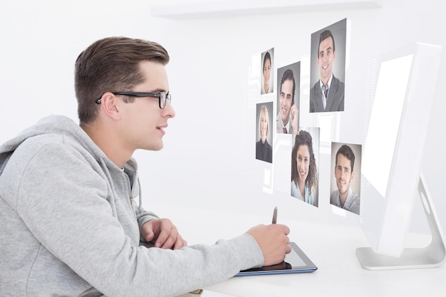 Casual man working at desk with computer and digitizer against profile pictures