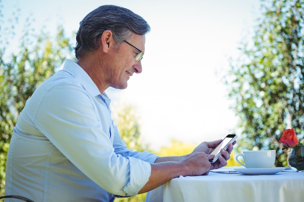 Uomo d'affari maturo casuale che per mezzo dello smartphone