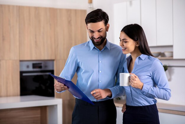 Casual mood Cheerful smiling colleagues standing in the kitchen and discussing their project