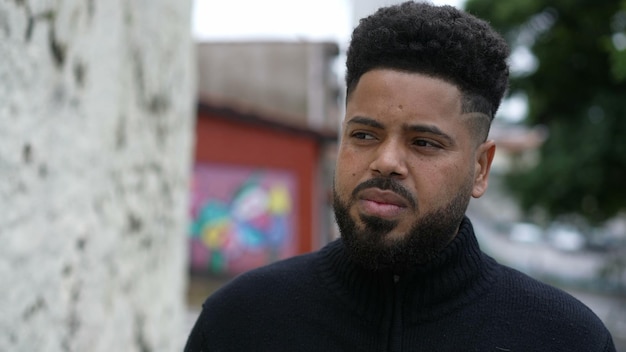 A casual pensive young black standing in urban street outside