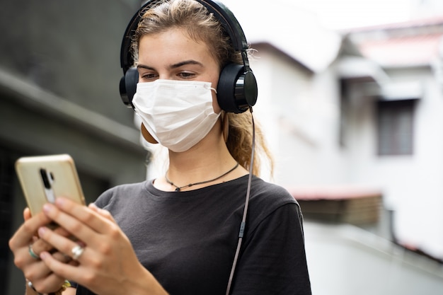 Casual portrait of a girl on the street covering the face with a face mask