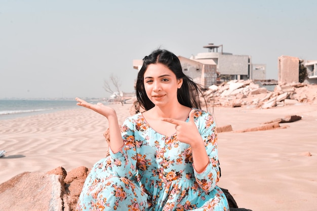 casual pretty girl front pose at beach pointing aside indian pakistani model