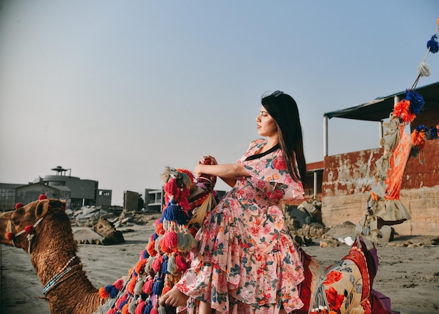 casual pretty girl side pose sitting camel at beach indian pakistani model