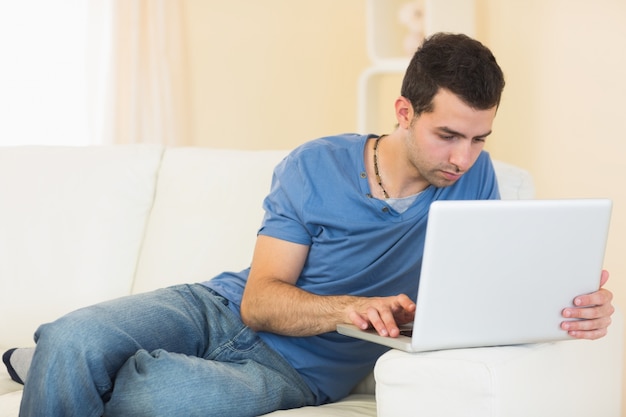 Casual rustige man zittend op de bank met behulp van laptop