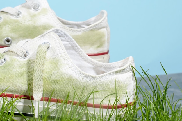 Casual schoenen in gras vlekken dagelijks leven vlek concept ruimte voor tekst geïsoleerd op blauwe achtergrond