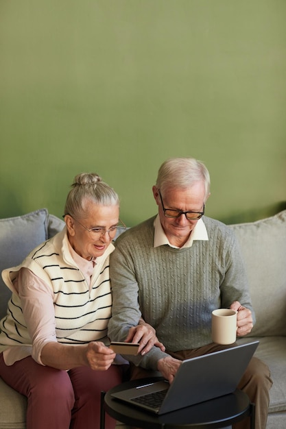 Casual senior man and woman sitting on couch in front of laptop