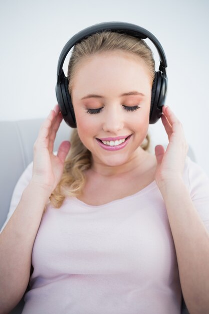 Случайные улыбается блондинка слушать музыку с закрытыми глазами