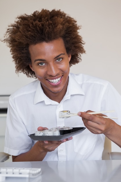 Casual uomo d'affari sorridente mangiare sushi alla sua scrivania