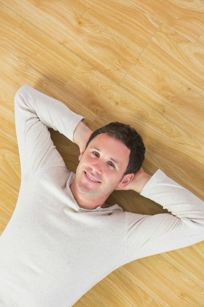 Случайный улыбающийся человек, лежа на полу, глядя на камеру