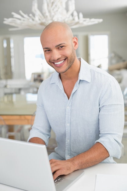 Casual smiling man using laptop at home