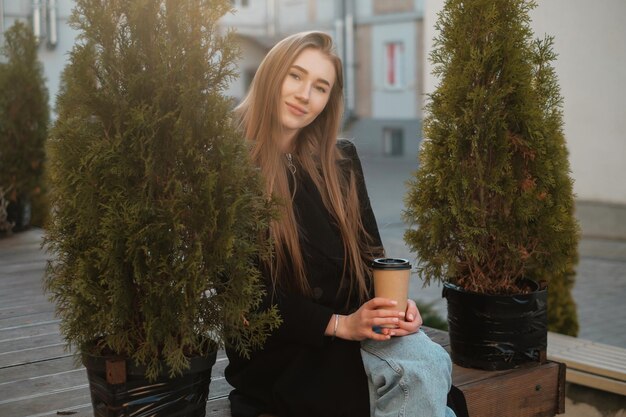 Casual straat vrouwelijk portret Dame met lang haar die koffie neemt en naar de camera kijkt