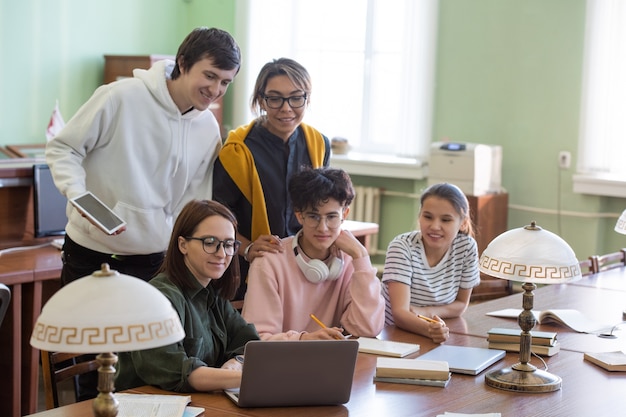 Casual studenten kijken naar online videolessen op laptop terwijl ze zich voorbereiden op een conferentie of seminar in de universiteitsbibliotheek