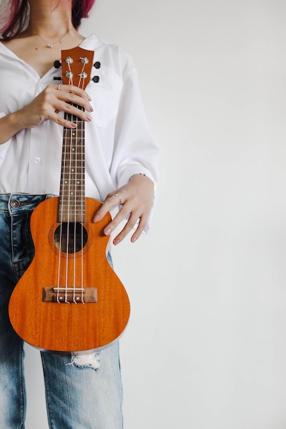 Casual and stylish young girl hold ukulele guitar copy space
for art and musical concept