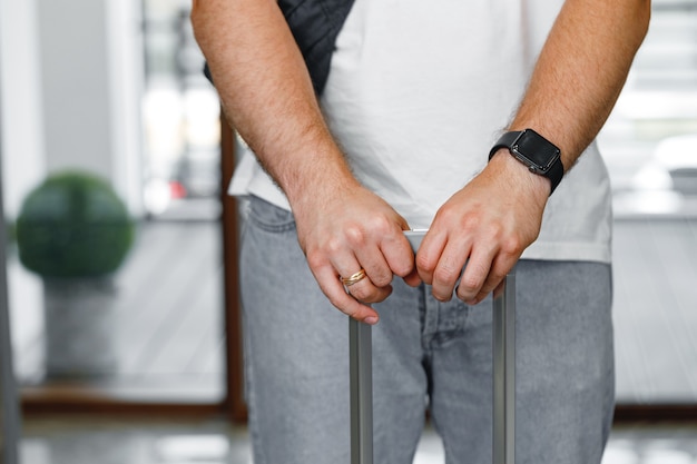 Casual unrecognizable man standing with luggage suitcase close up