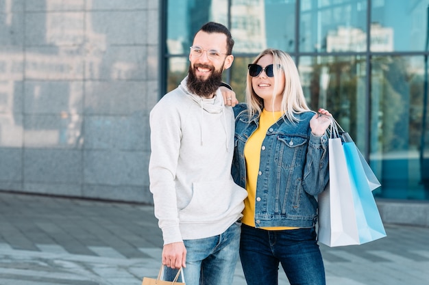 Casual urban shopping couple Retail sale lifestyle Smiling man and woman with paper bags