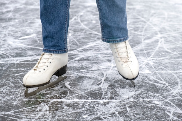 Foto casual vrouw kijken in schaatsen en jeans op ijs